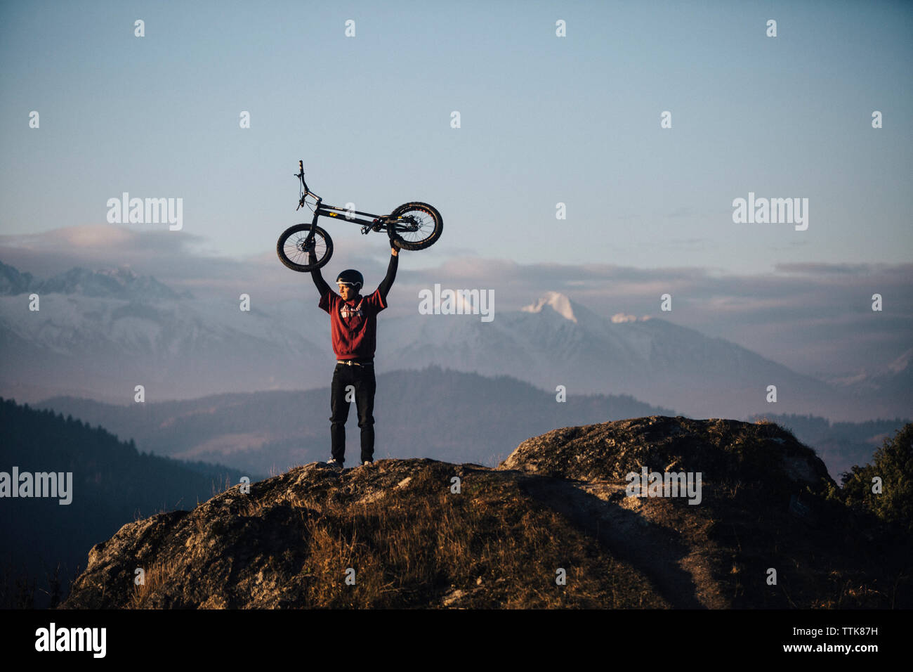 young men carrying bmx over his head on the rock, Slovakia Stock Photo