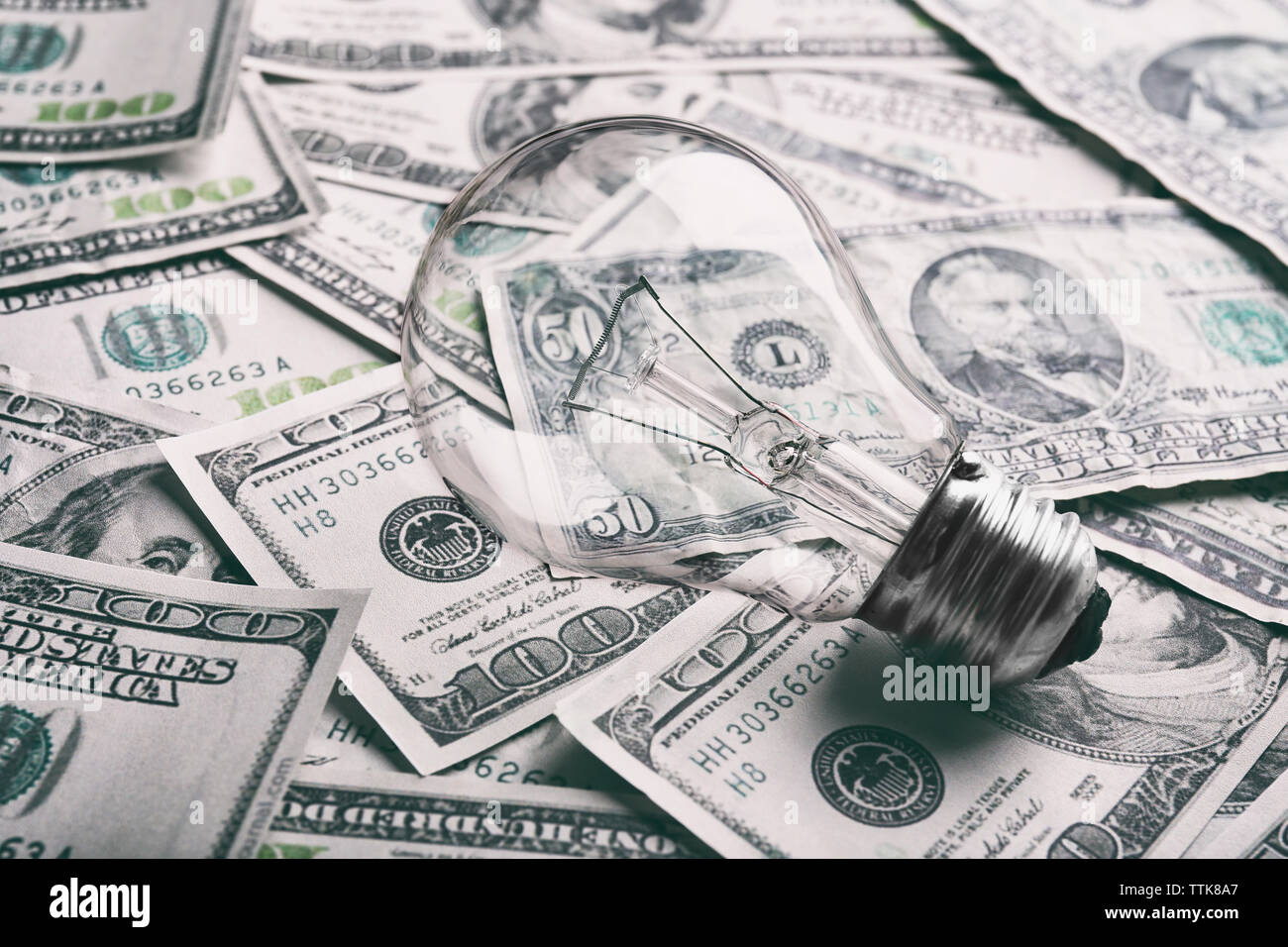 Electric bulb on dollars background Stock Photo - Alamy