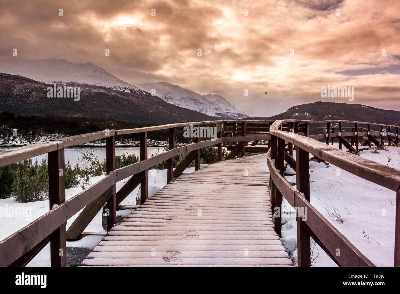 Footbridge against cloudy sky during winter Stock Photo