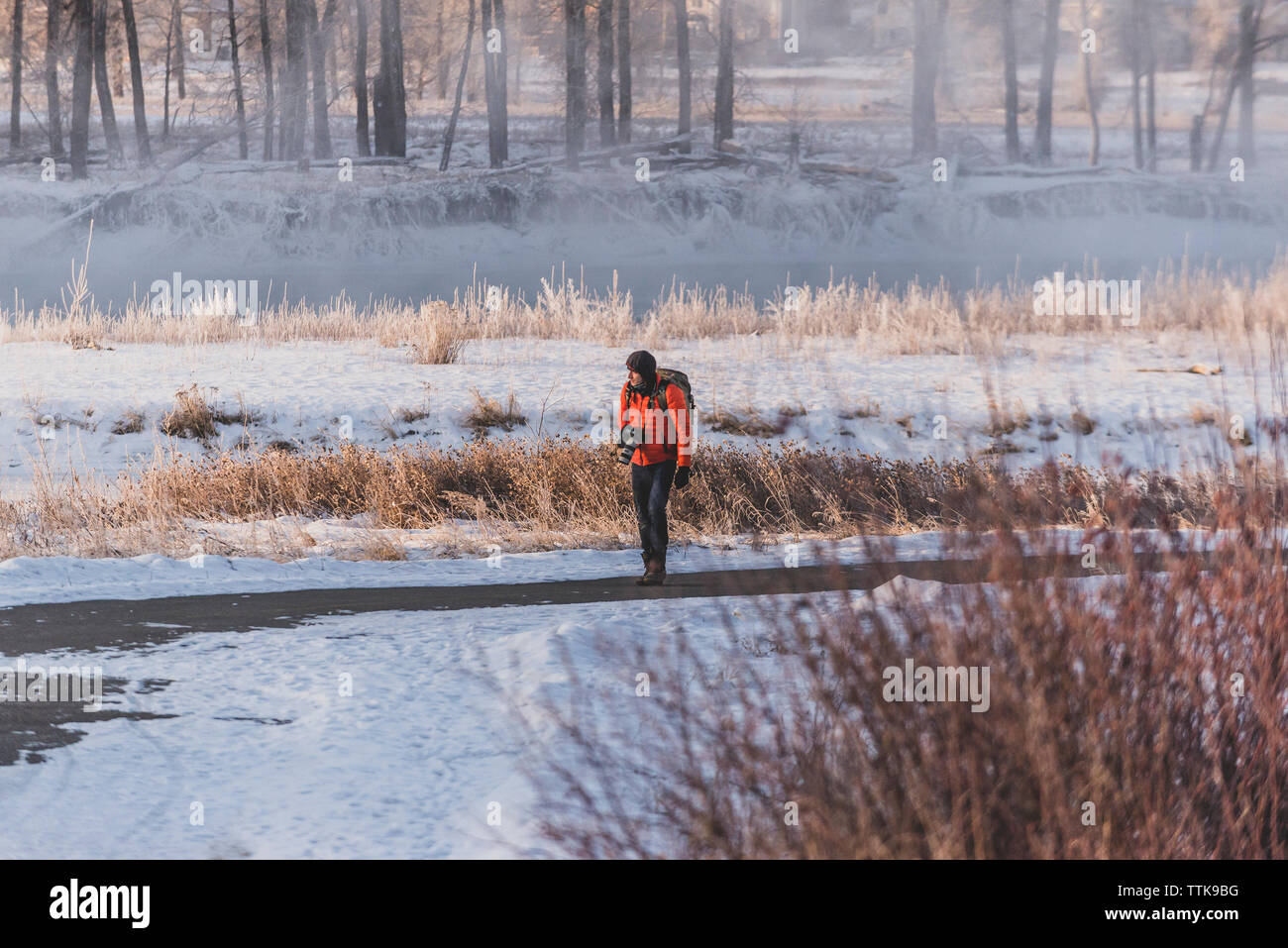 Photographer walking on bike path next to frozen river in Calgary Stock Photo