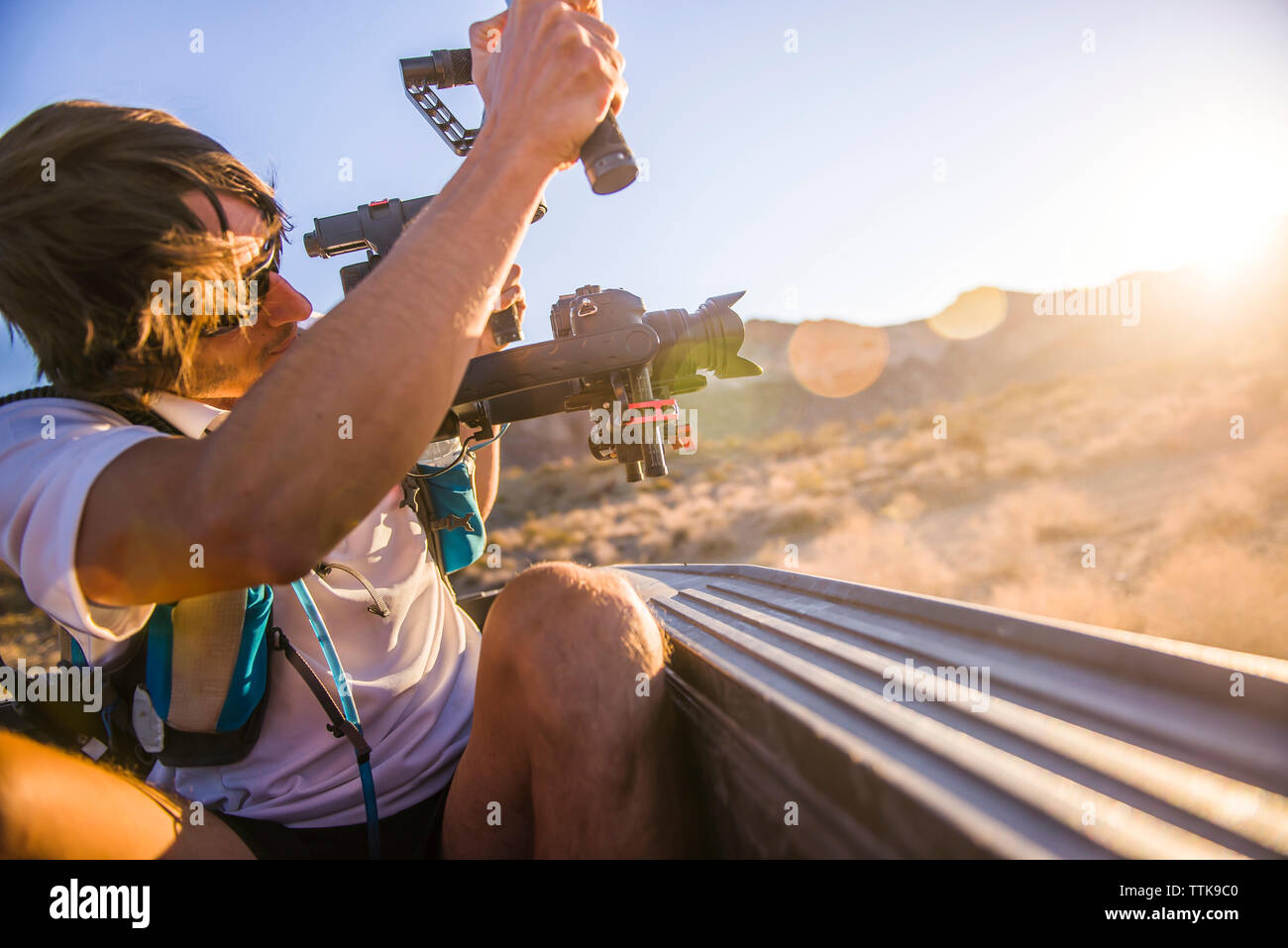 Photographer Videographer shooting sunset with Gimbal from truck bed Stock Photo