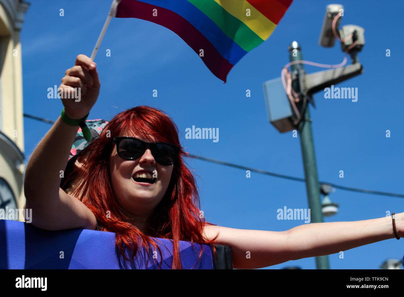 Red-headed woman waving rainbow flag at Helsinki Pride Parade 2016 in Helsinki, Finland Stock Photo