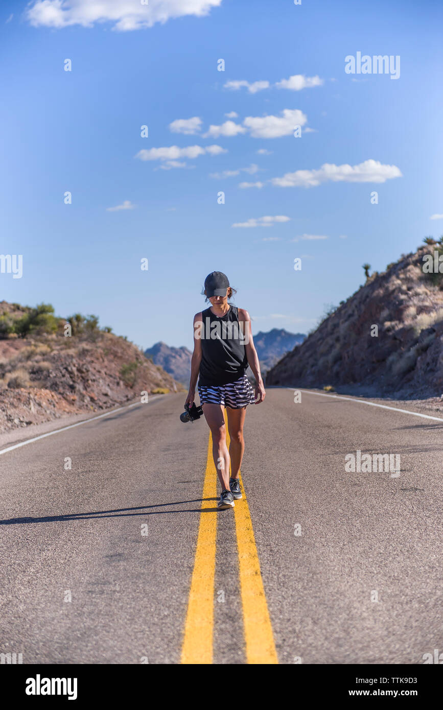 Young Woman Travel Photographer walking in the middle of the road Stock Photo