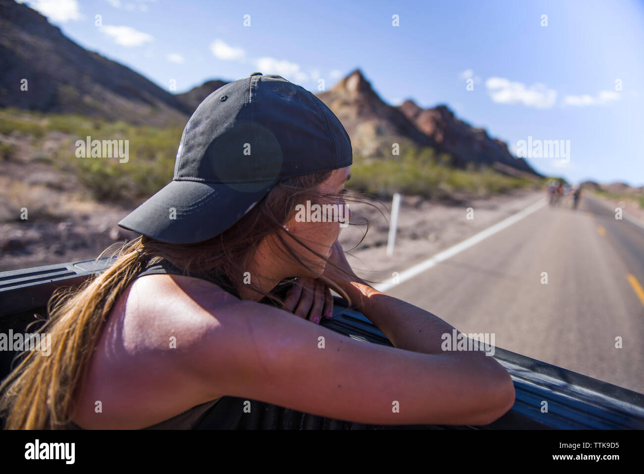 Young Woman Enjoying Mountain View from back of truck Stock Photo