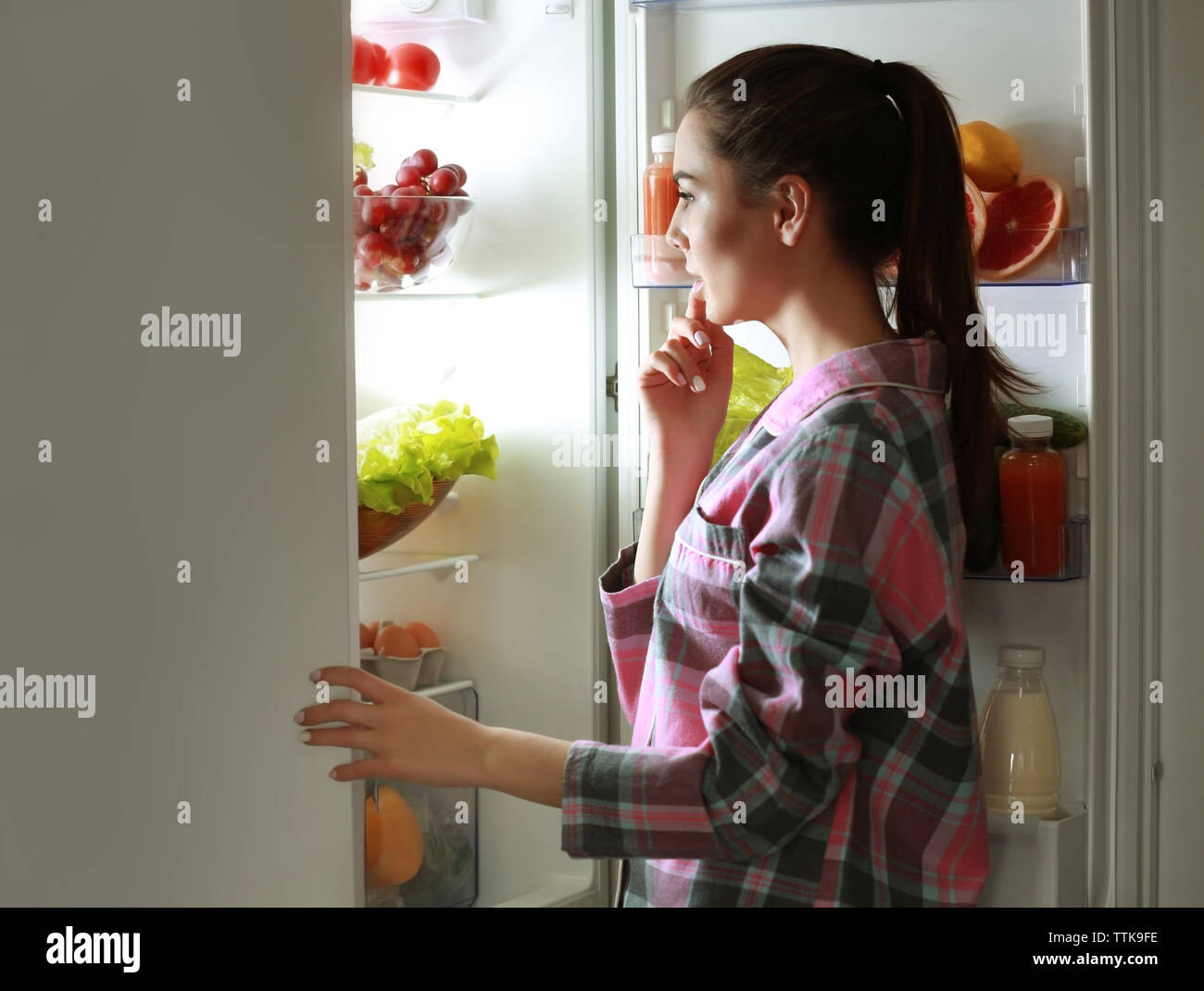 Вечером сильно хочется есть. Девочка у холодильника. Ужин перед сном. Заглядывая в холодильник. Ночной перекус.