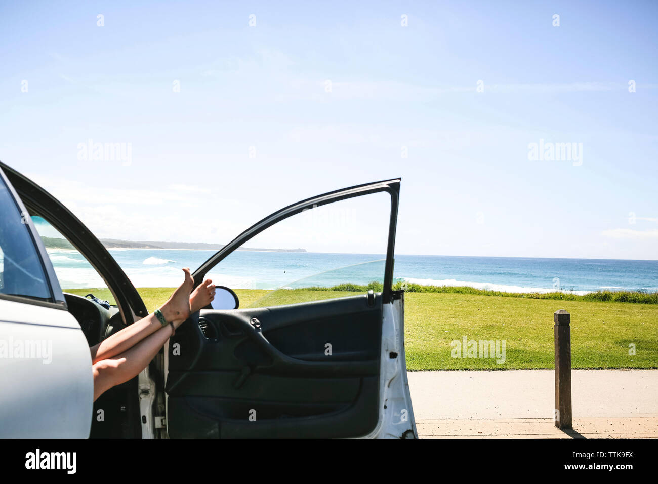 Low section of woman on car door against clear sky Stock Photo