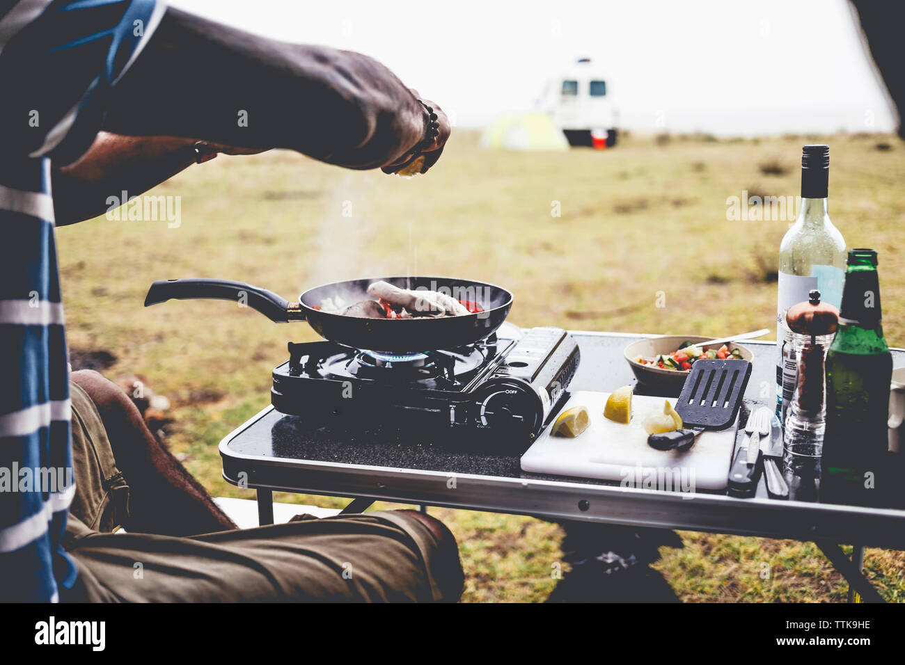 Cropped image of man preparing food on camping stove at campsite Stock Photo