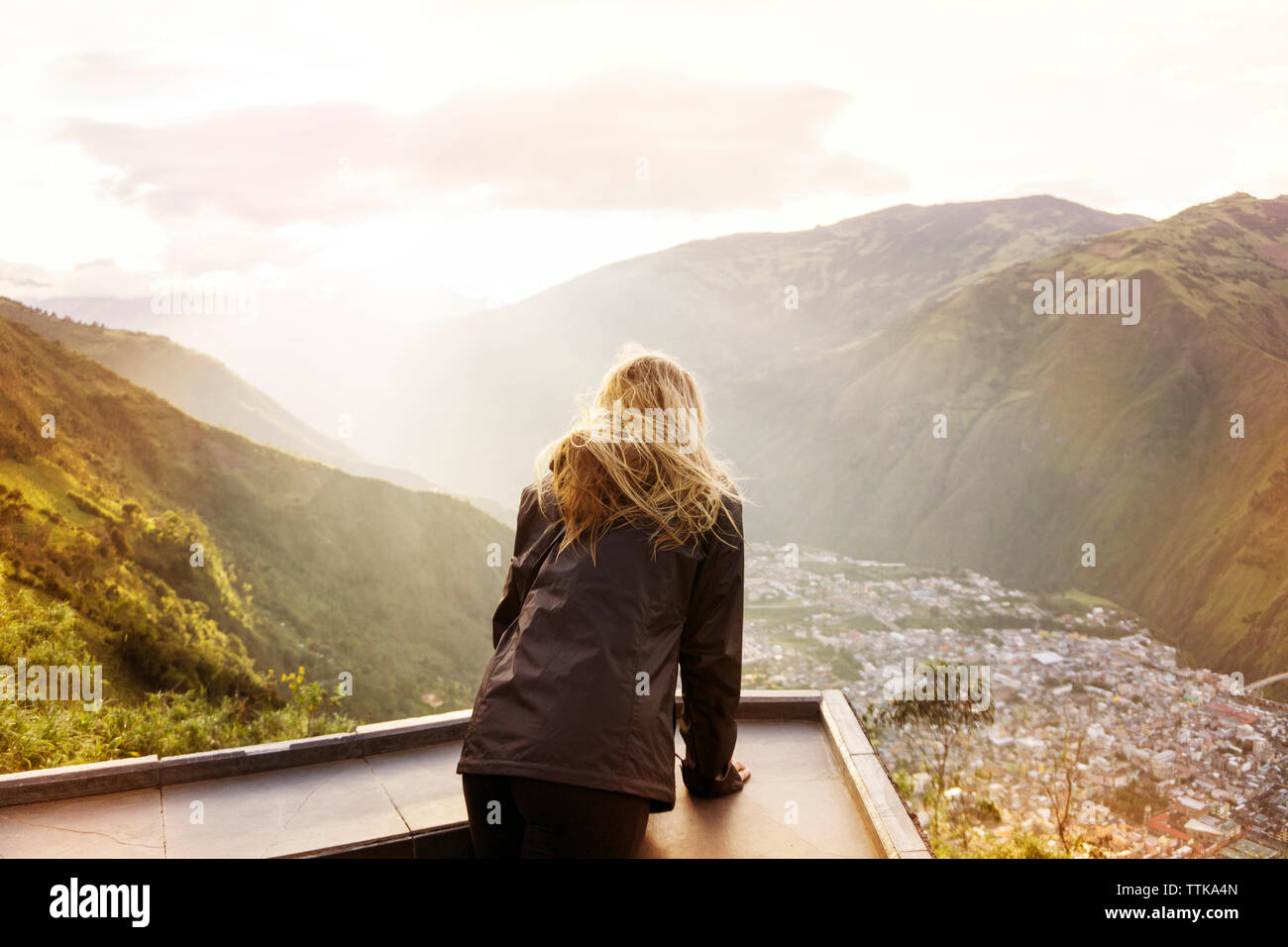 Rear view of woman standing at observation point against mountains and sky Stock Photo