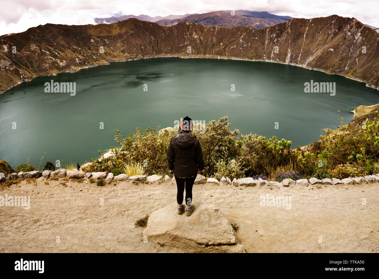 Rear view of woman standing on rock against Quilotoa Stock Photo