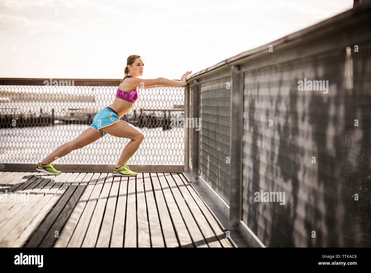 Woman stretching by railing against clear sky Stock Photo