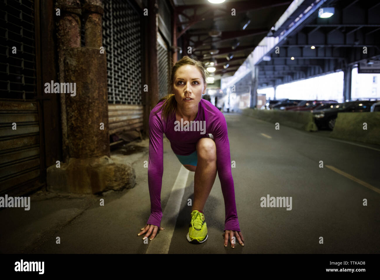 Front view of woman in starting position ready to run by bridge Stock Photo