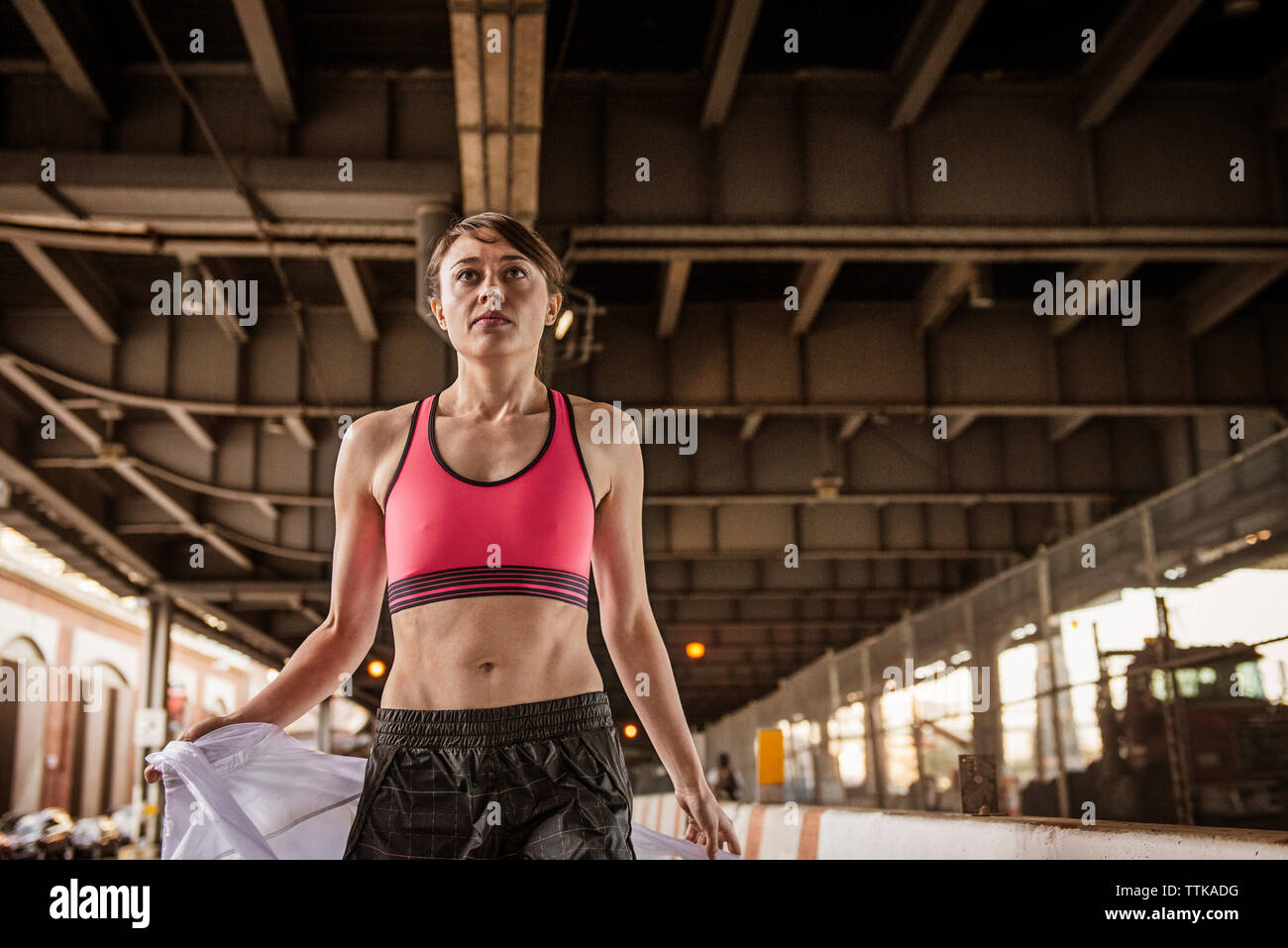 Confident woman wearing sports bra standing under bridge Stock Photo