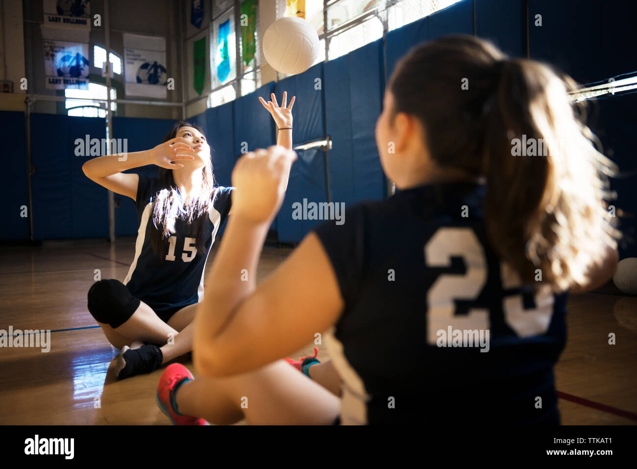 Girls playing catch with volleyball on floor Stock Photo Alamy
