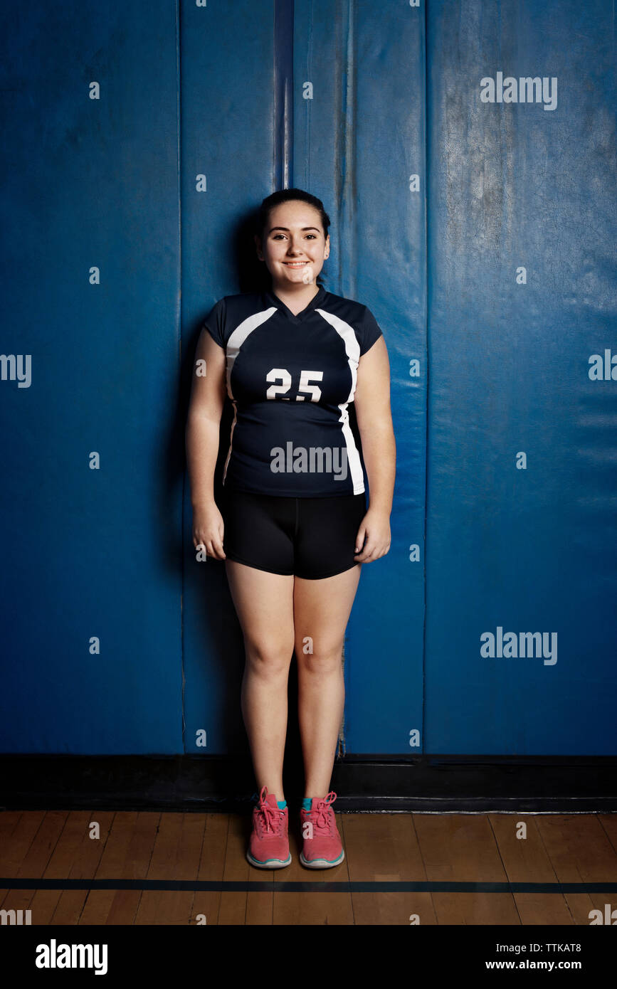 Portrait of smiling girl standing against blue wall Stock Photo - Alamy