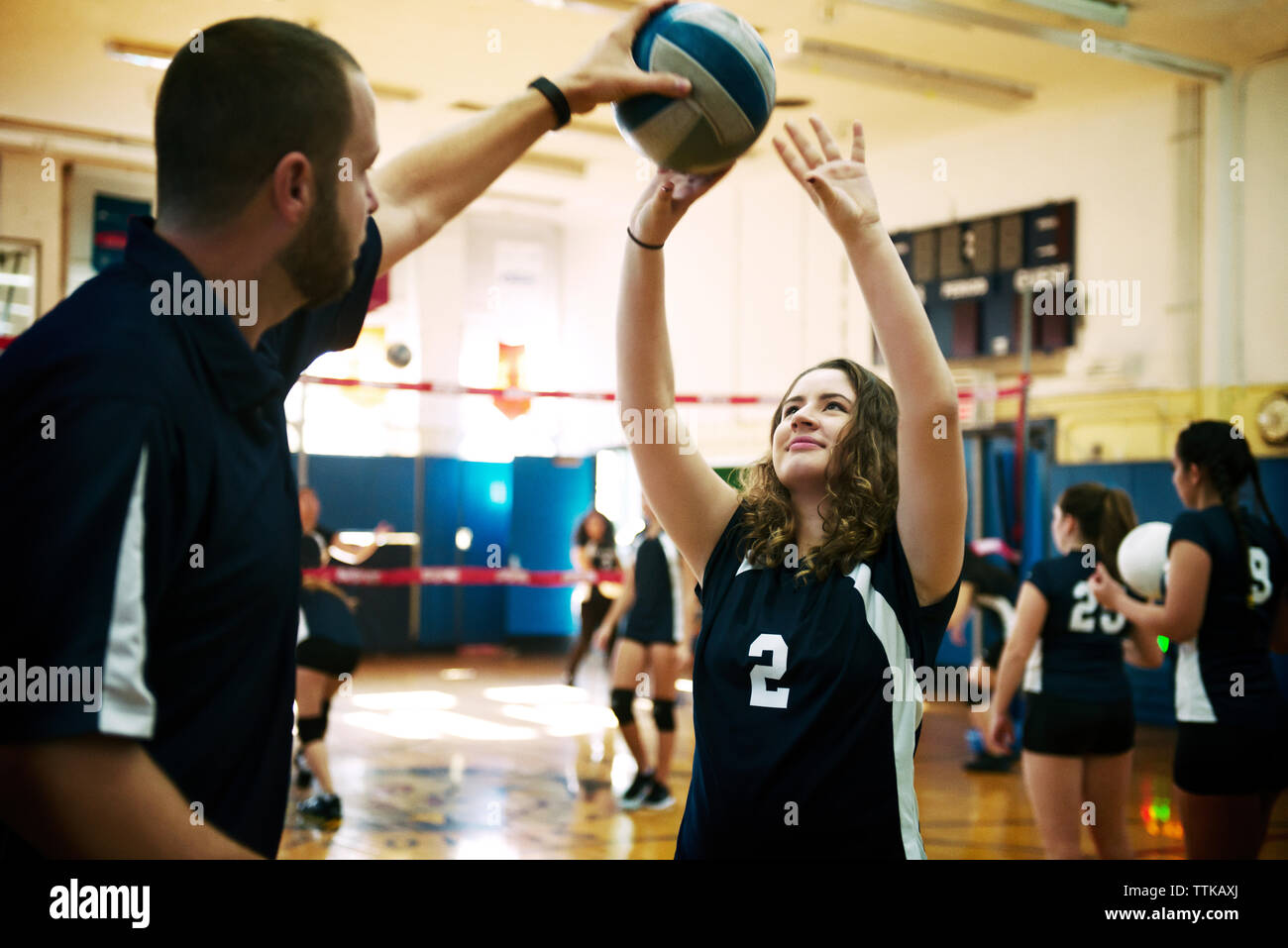 Male coach teaching girl in volleyball court Stock Photo