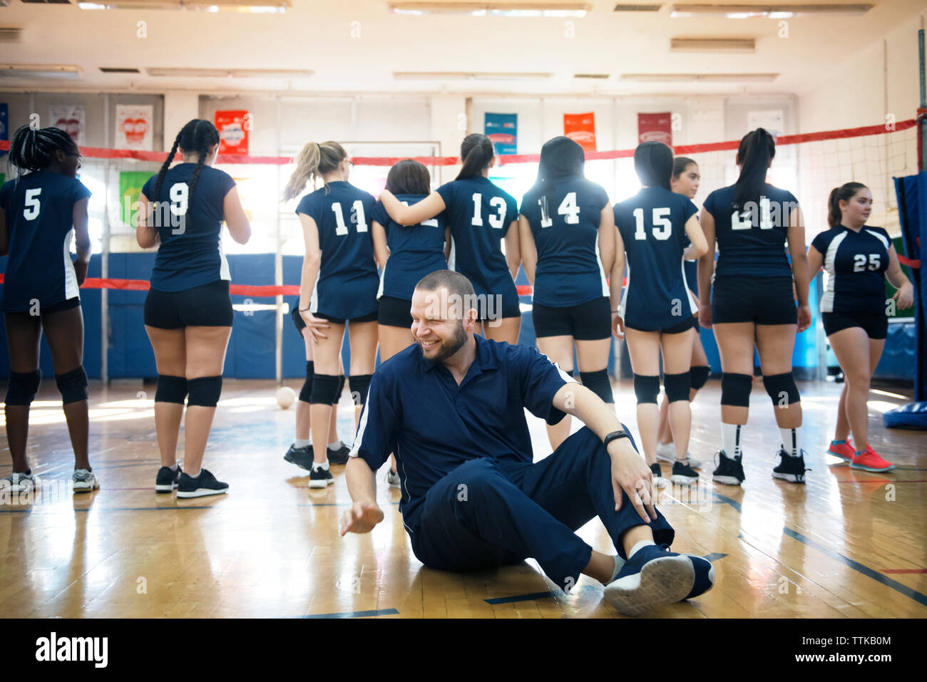 Male coach with female sports team in court Stock Photo