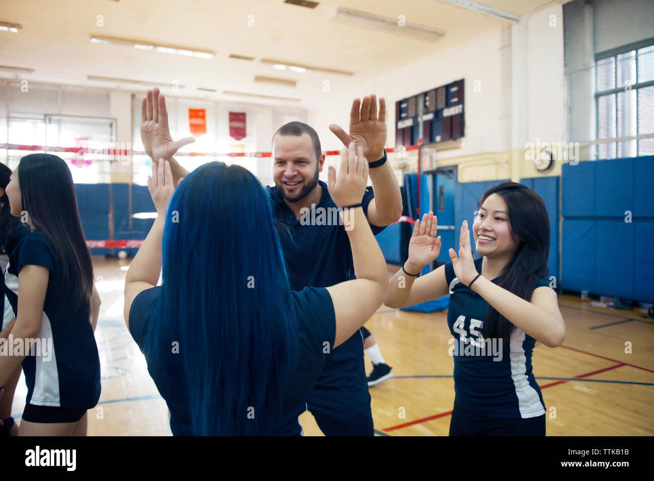 Teenage girls celebrating with male coach in court Stock Photo