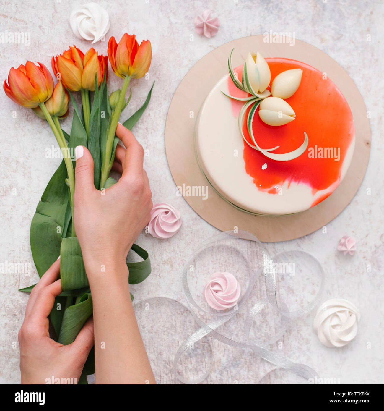 Cropped hands of woman arranging flowers by cake on table at home Stock Photo