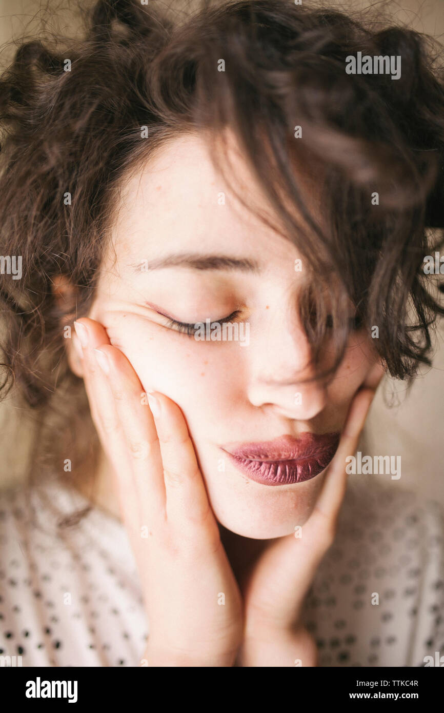 Close-up of woman with hand on chin puckering lips at home Stock Photo