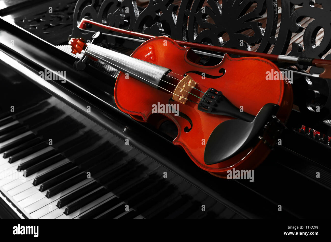 Violin lying on piano, close up Stock Photo