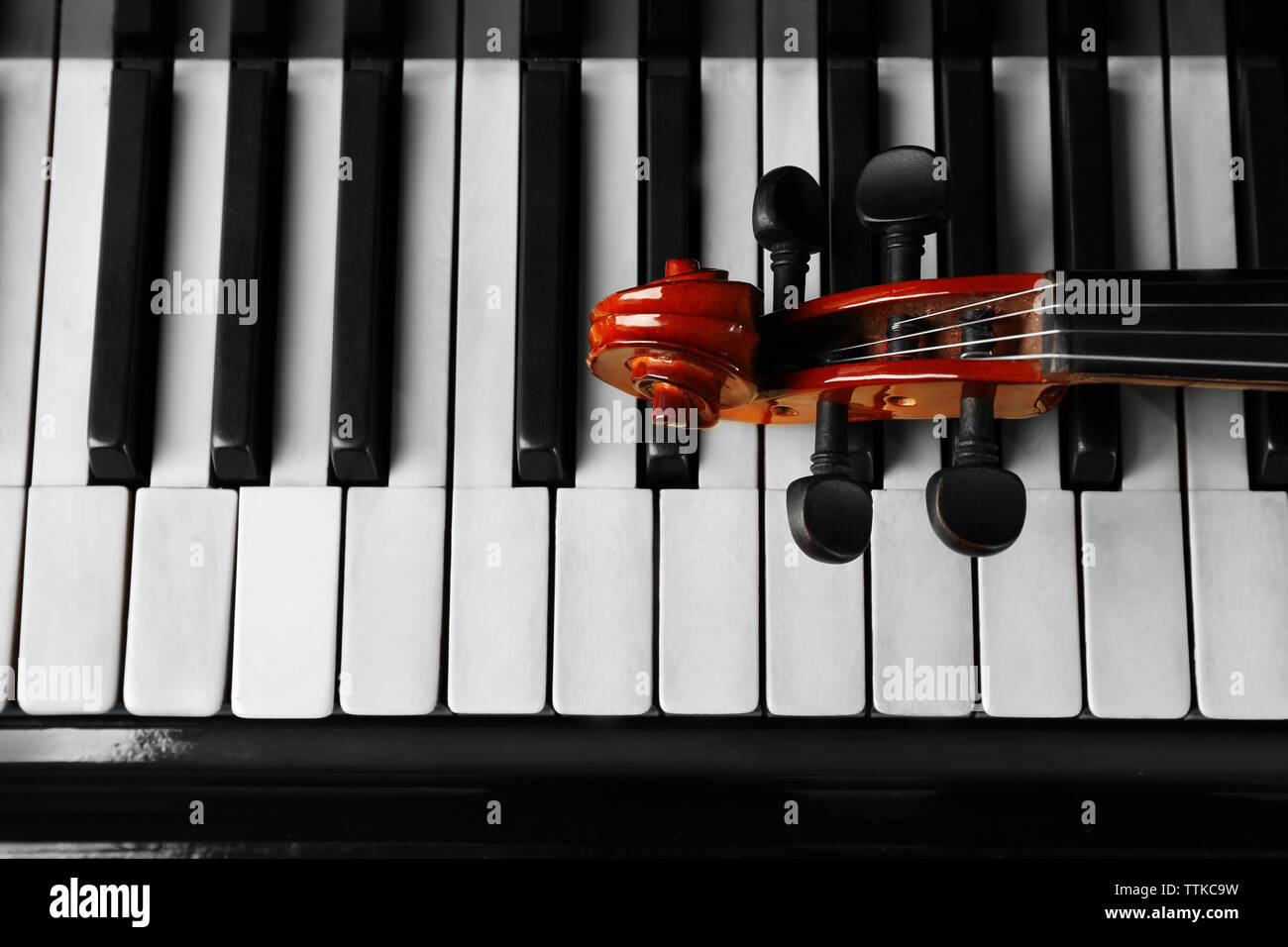 Violin neck lying on piano keys, close up Stock Photo