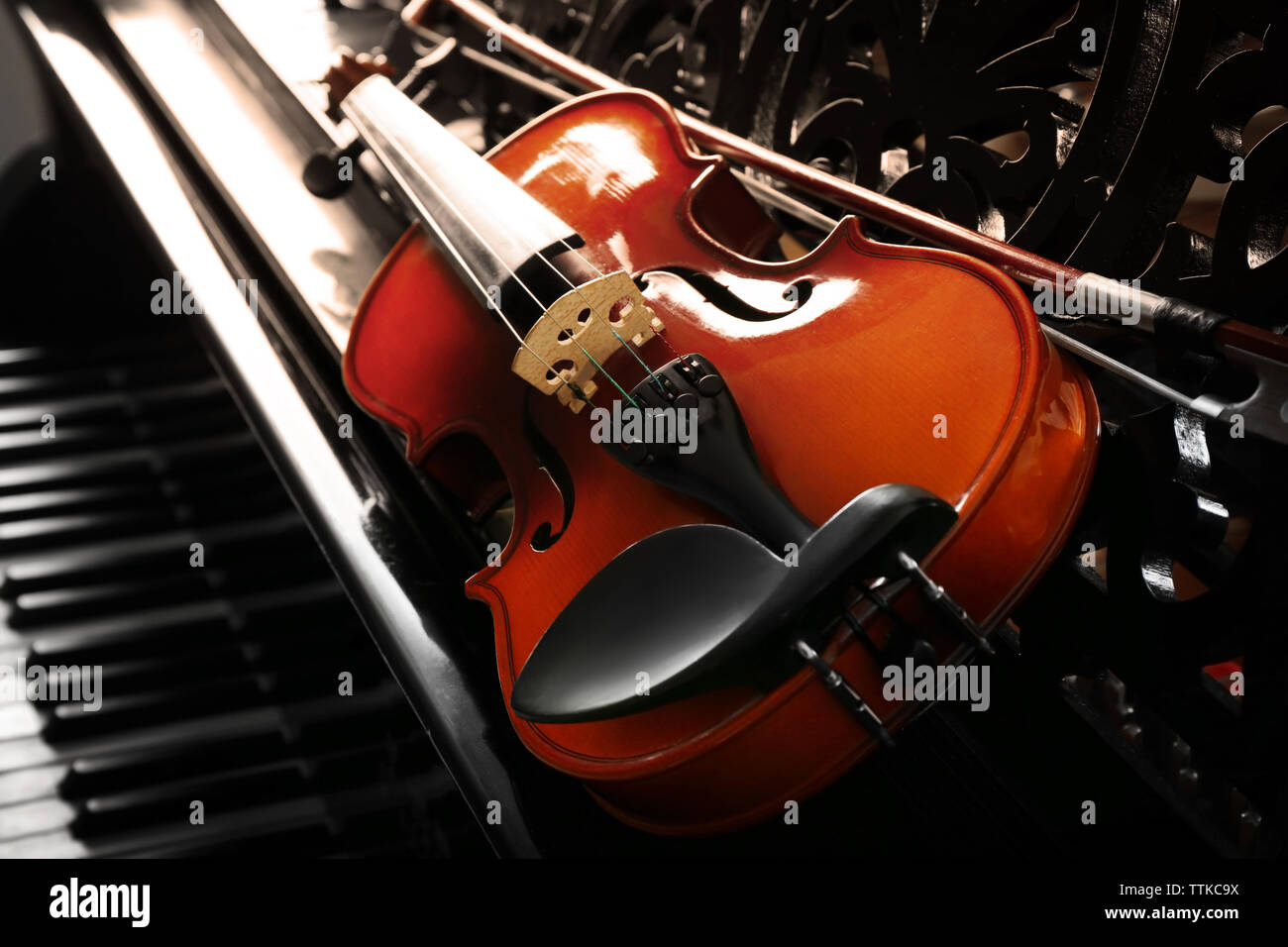 Violin lying on piano, close up Stock Photo