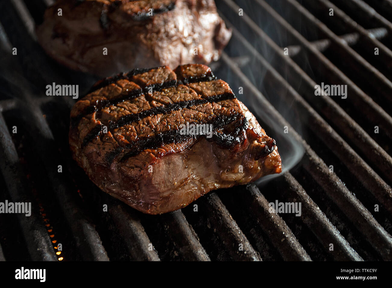 close up of charbroiled filet mignon beef cooking on infrared barbecue grill Stock Photo