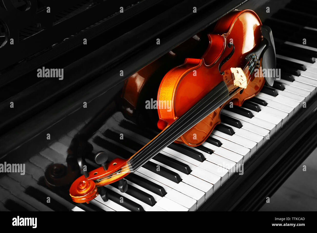 Violin lying on piano keys, close up Stock Photo