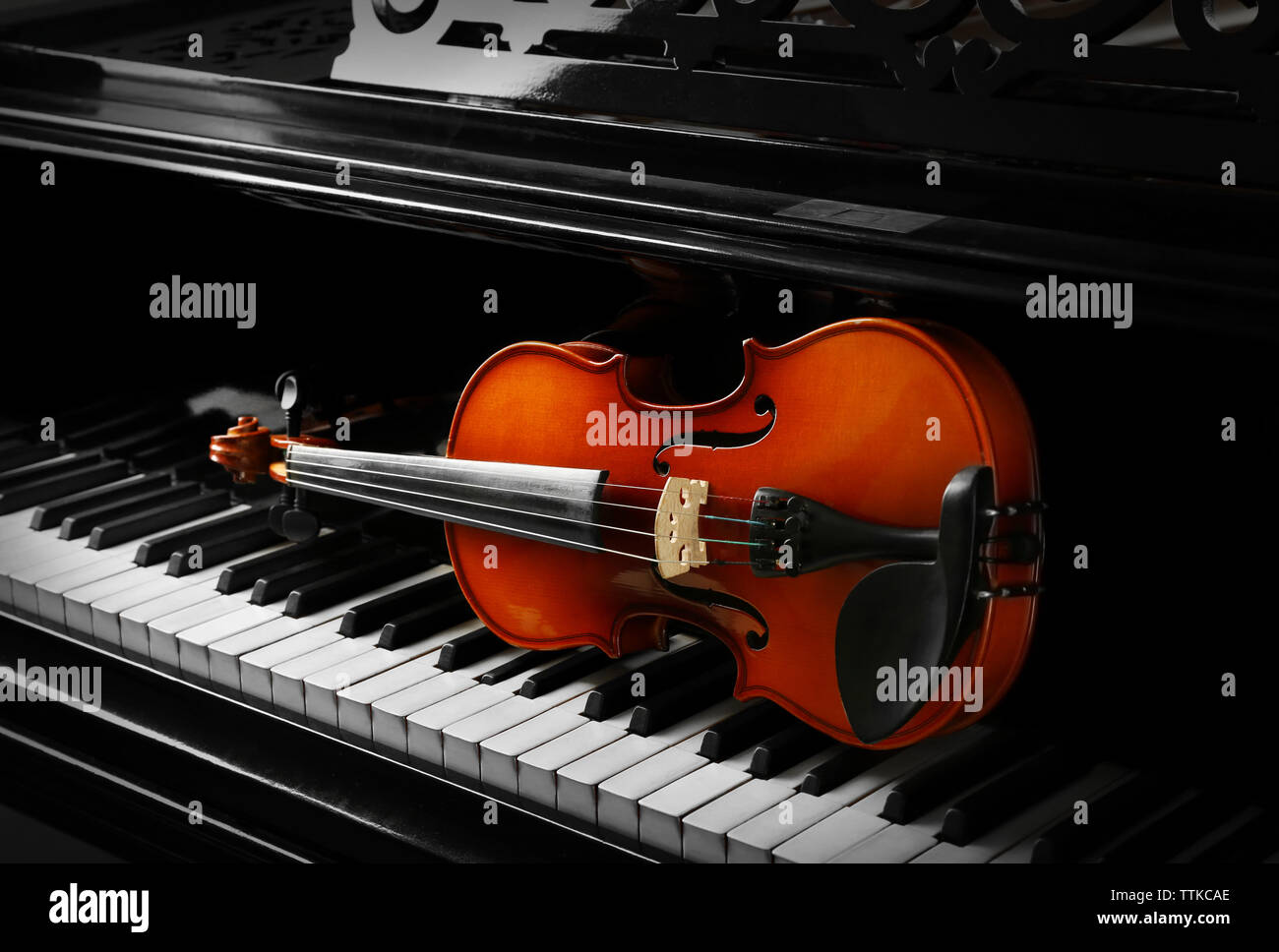 Violin lying on piano keys, close up Stock Photo