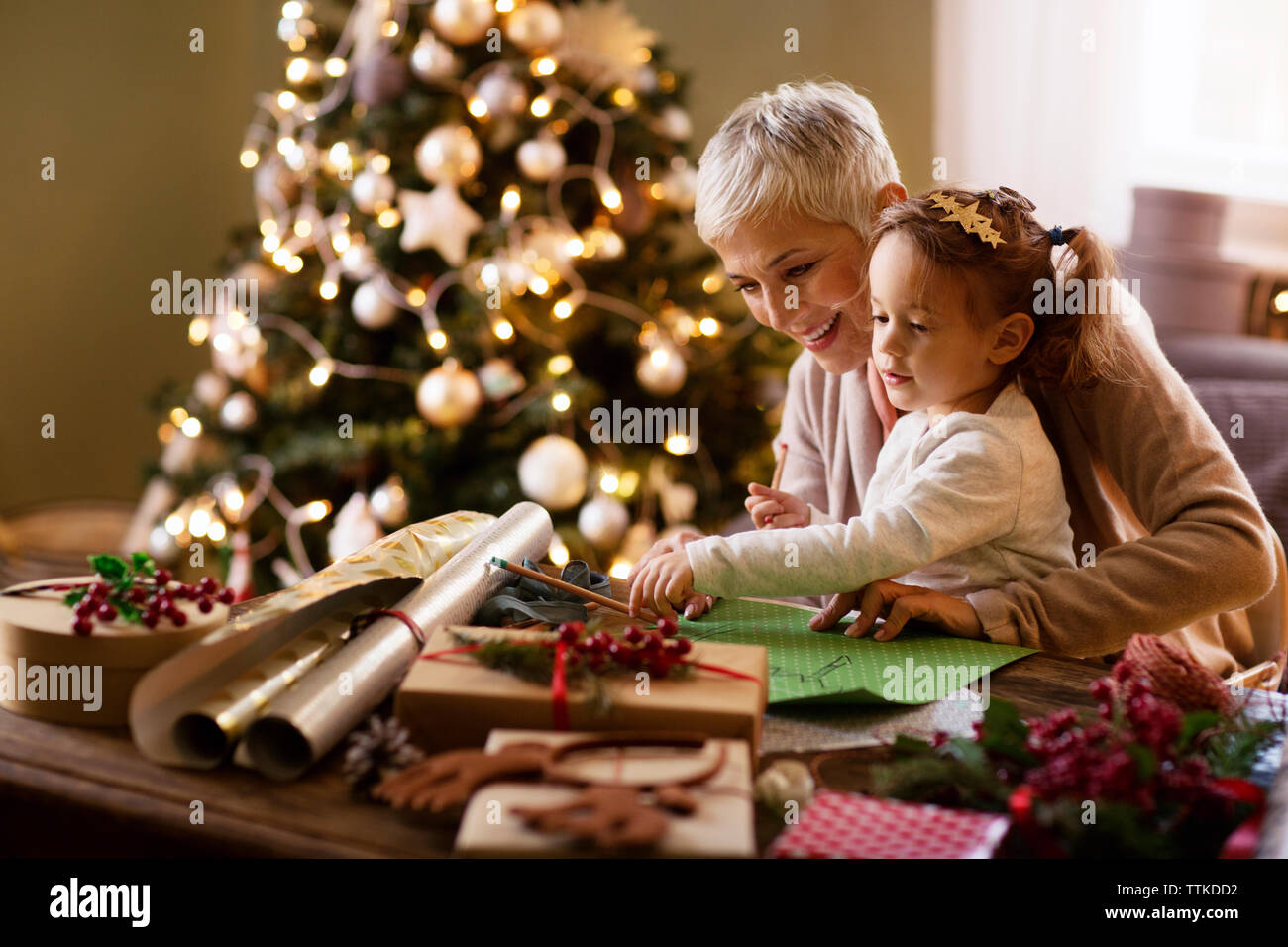 Grandmother assisting granddaughter in drawing at home Stock Photo