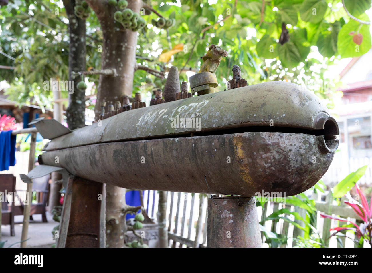 Casing of American cluster bomb dropped on Laos between 1967 to 1972 on display in restaurant garden, Muang Ngoi Neua, Muang Ngoi District, Luang Prab Stock Photo