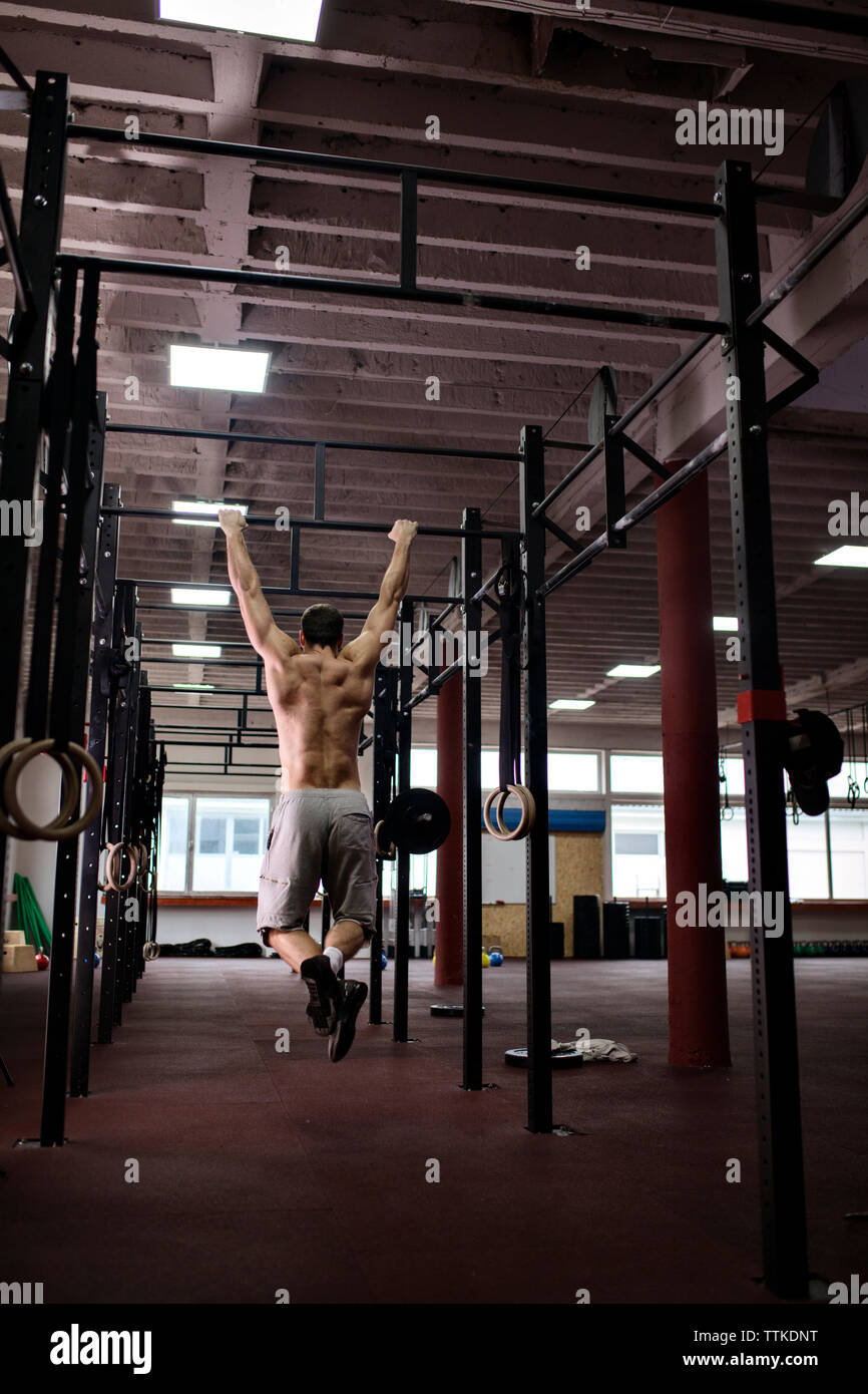 Rear view of man doing chin-ups in gym Stock Photo