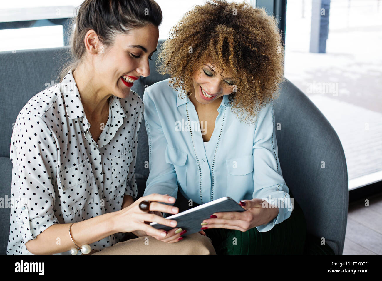 Cheerful female colleagues using tablet computer at cafe Stock Photo