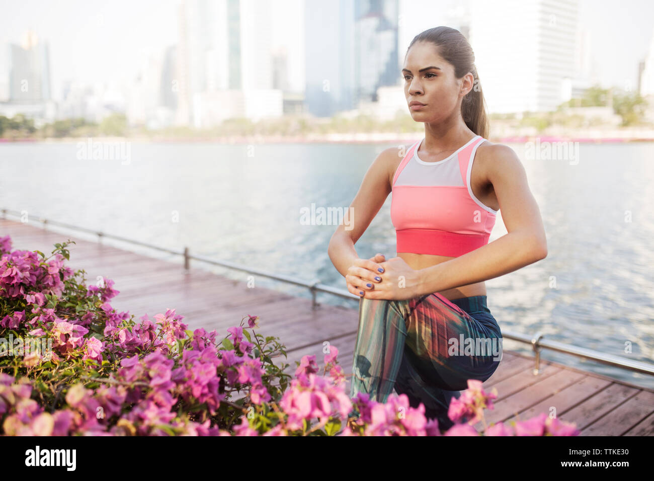 Woman exercising and stretching by plants at park Stock Photo