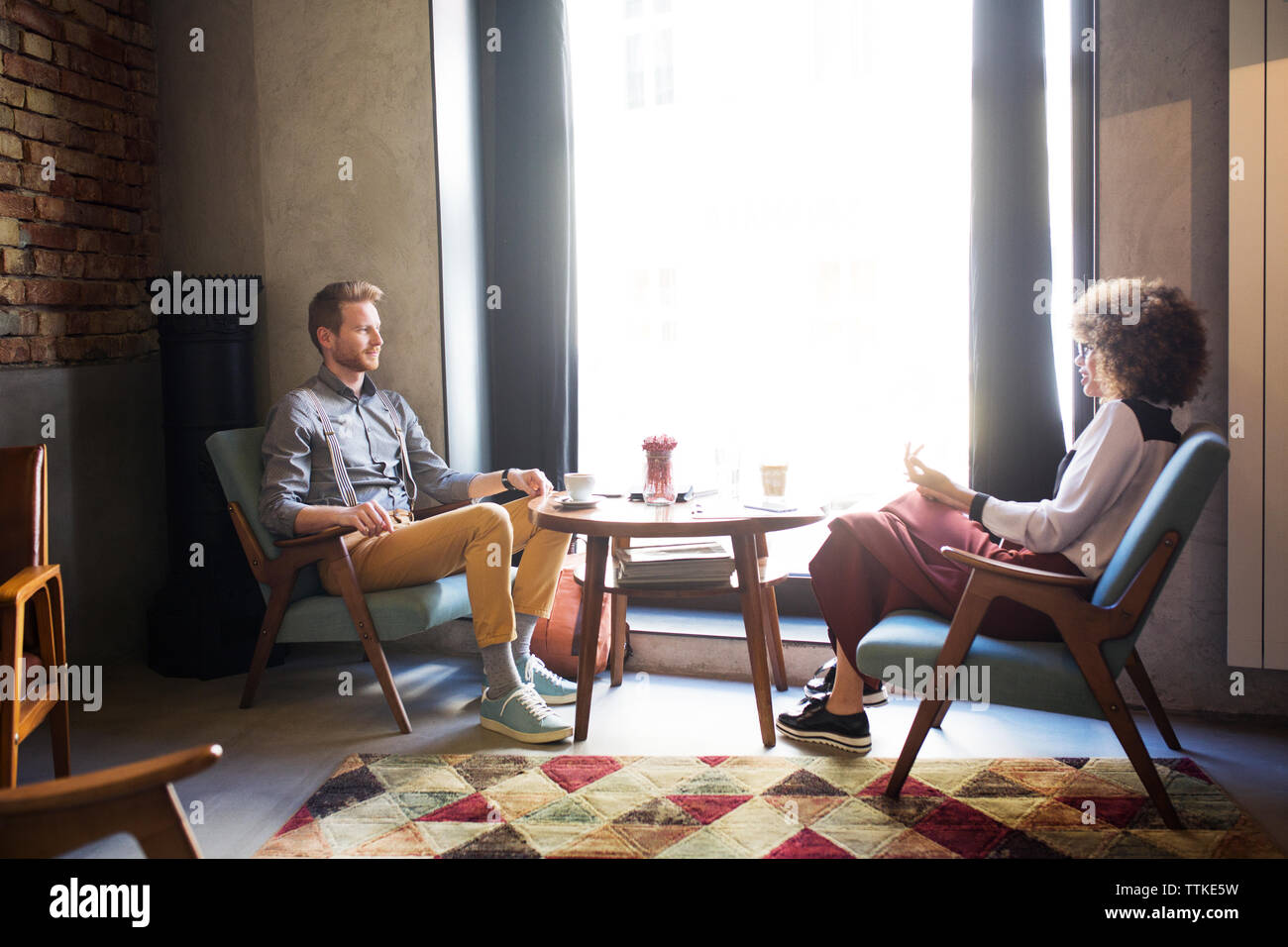 Business colleagues discussing by window at hotel lobby Stock Photo