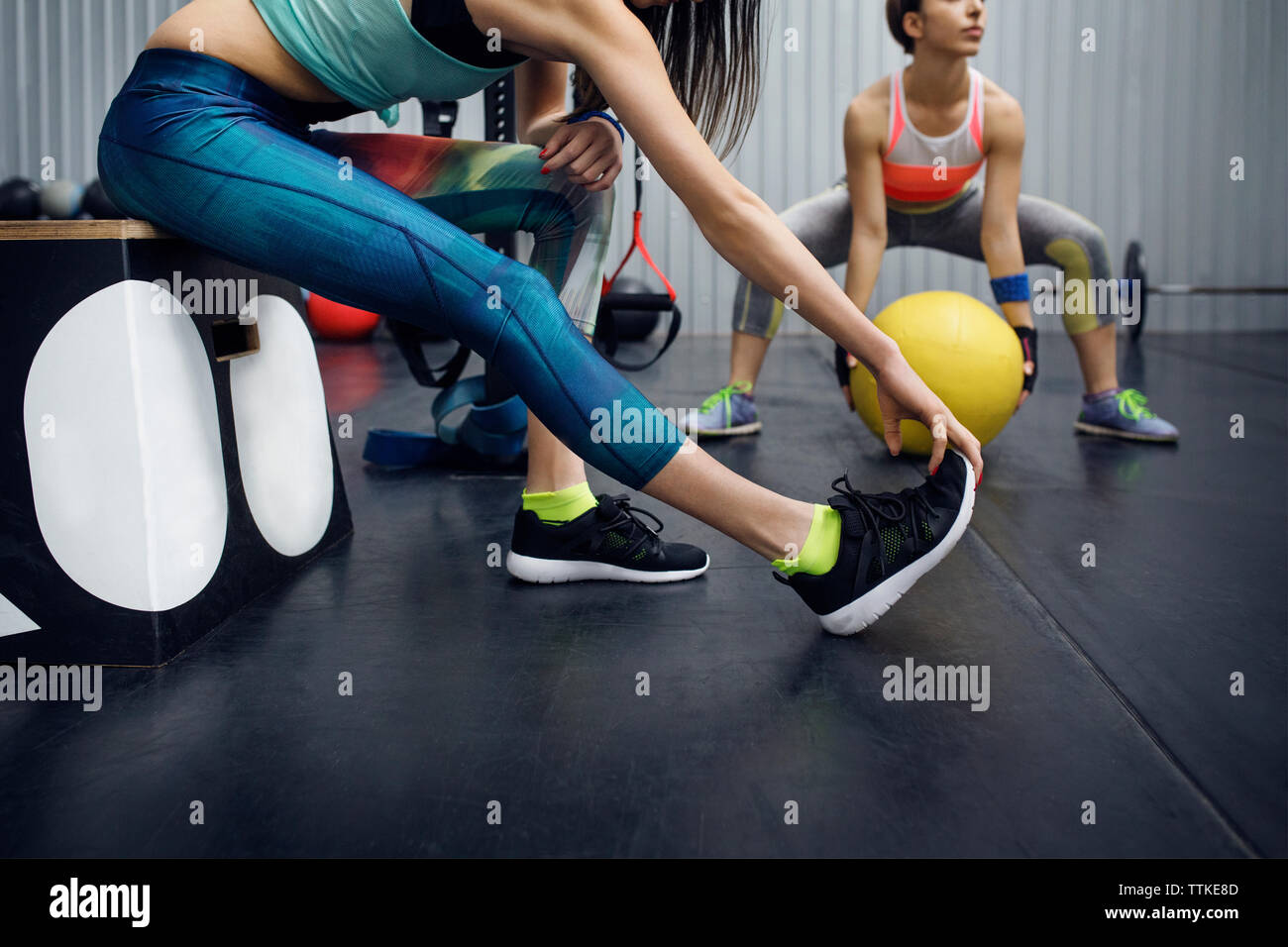 Low section of female athletes exercising in gym Stock Photo