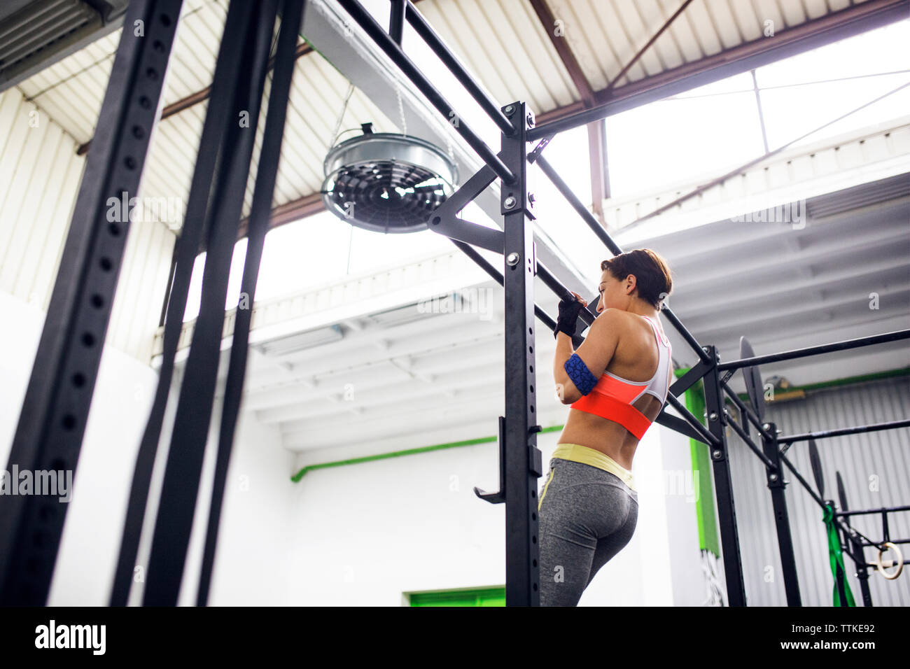 Low angle view of female athlete doing chin-ups at gym Stock Photo