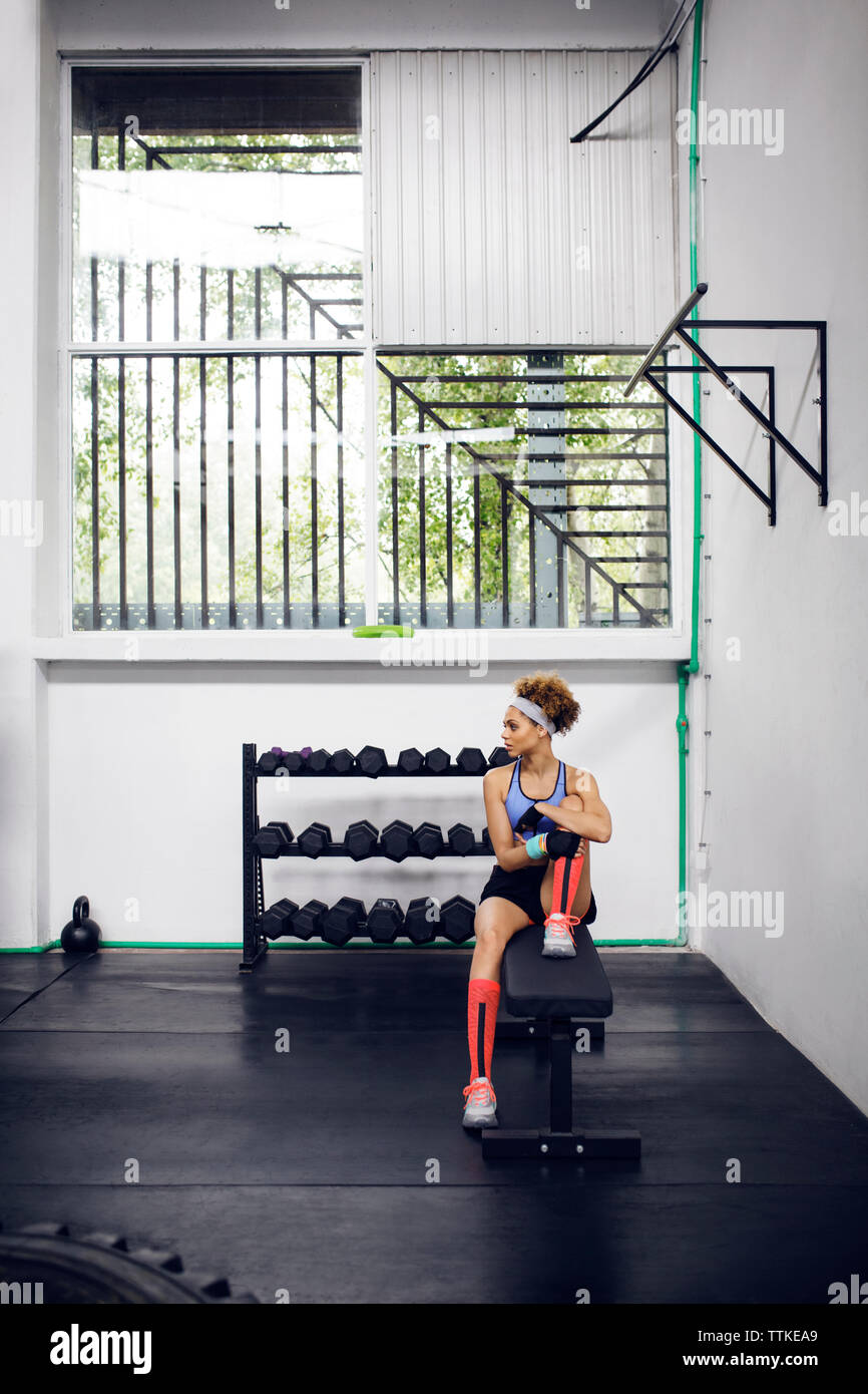 Thoughtful female athlete sitting on bench at gym Stock Photo - Alamy