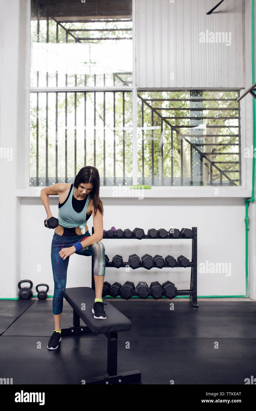 Determined female athlete lifting dumbbell at gym Stock Photo