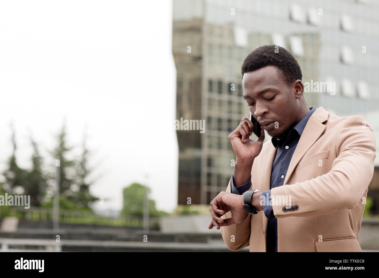 businessman checking the time while using smart phone in city Stock Photo