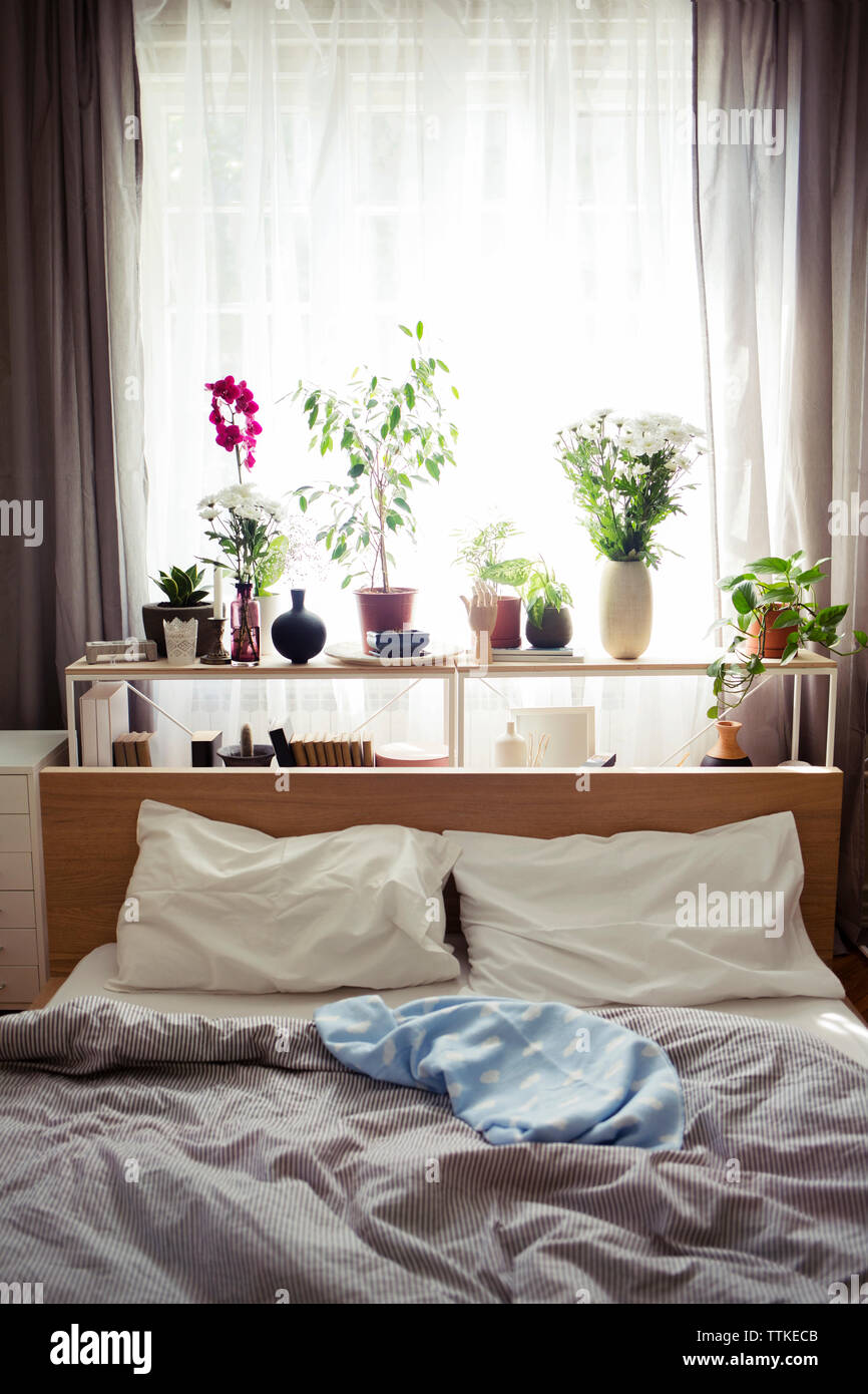 Unmade bed by window at home Stock Photo