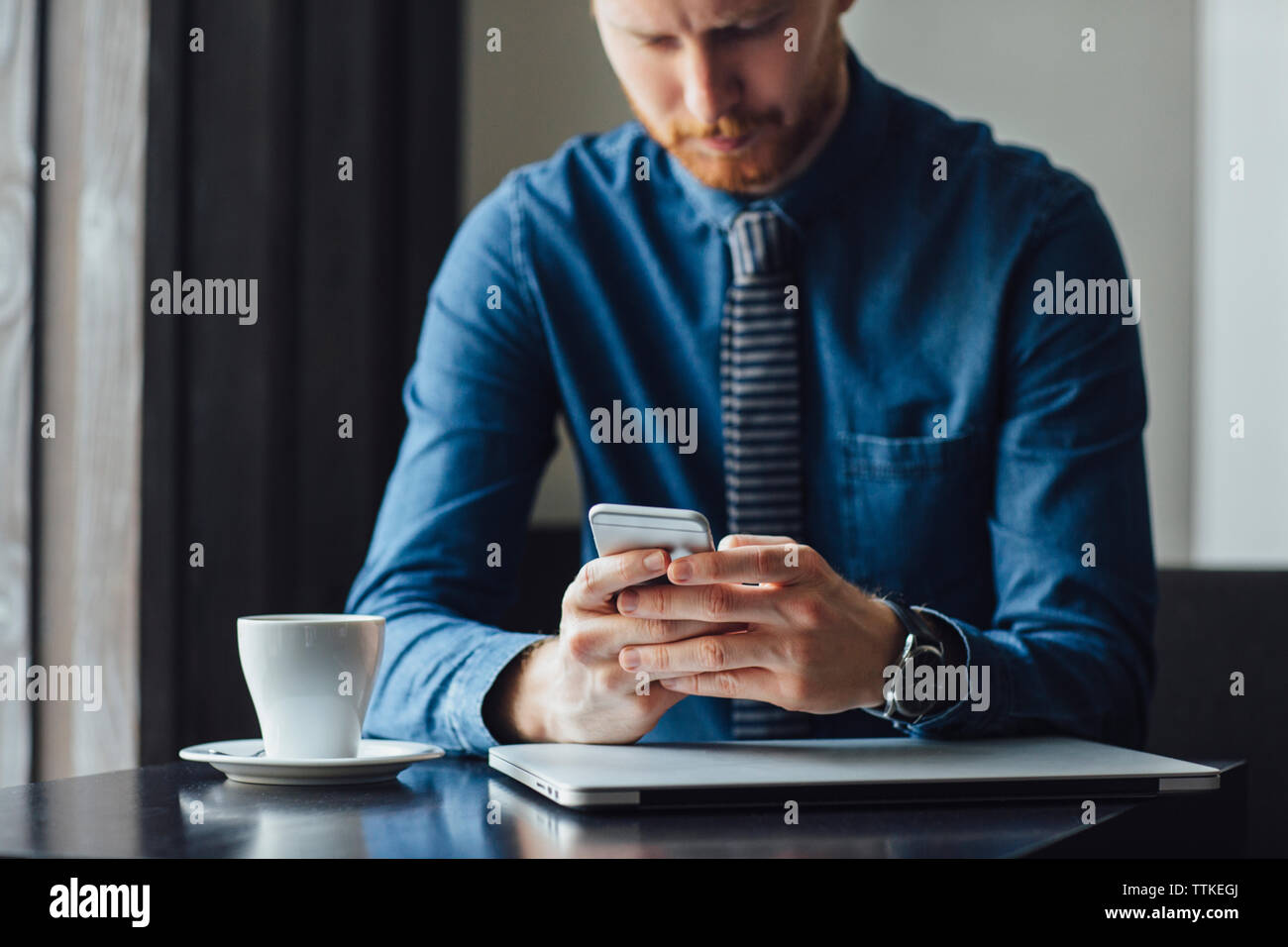 businessman using smart phone while sitting at restaurant table Stock Photo