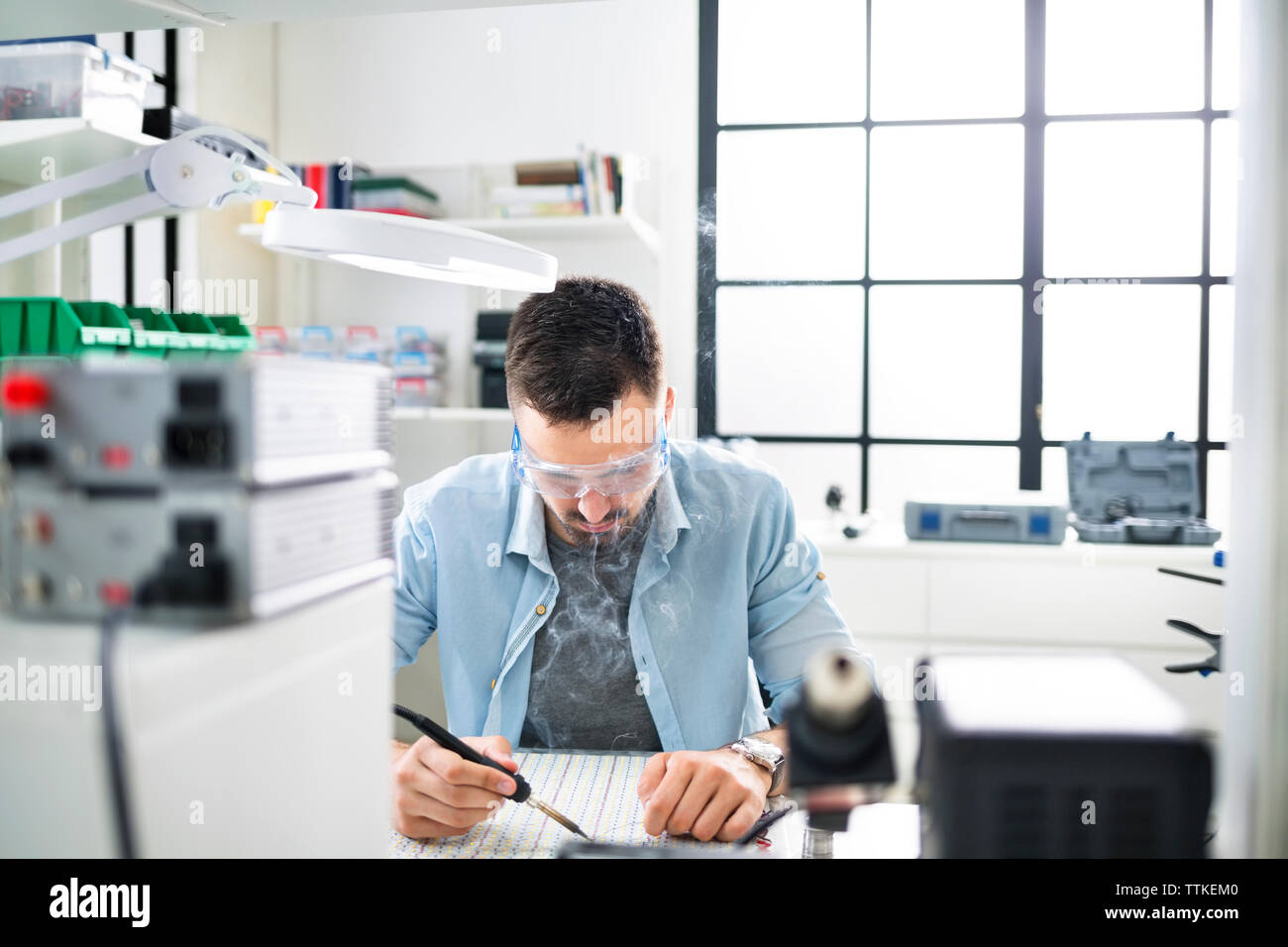 Serious engineer soldering circuit board at electronics laboratory Stock Photo