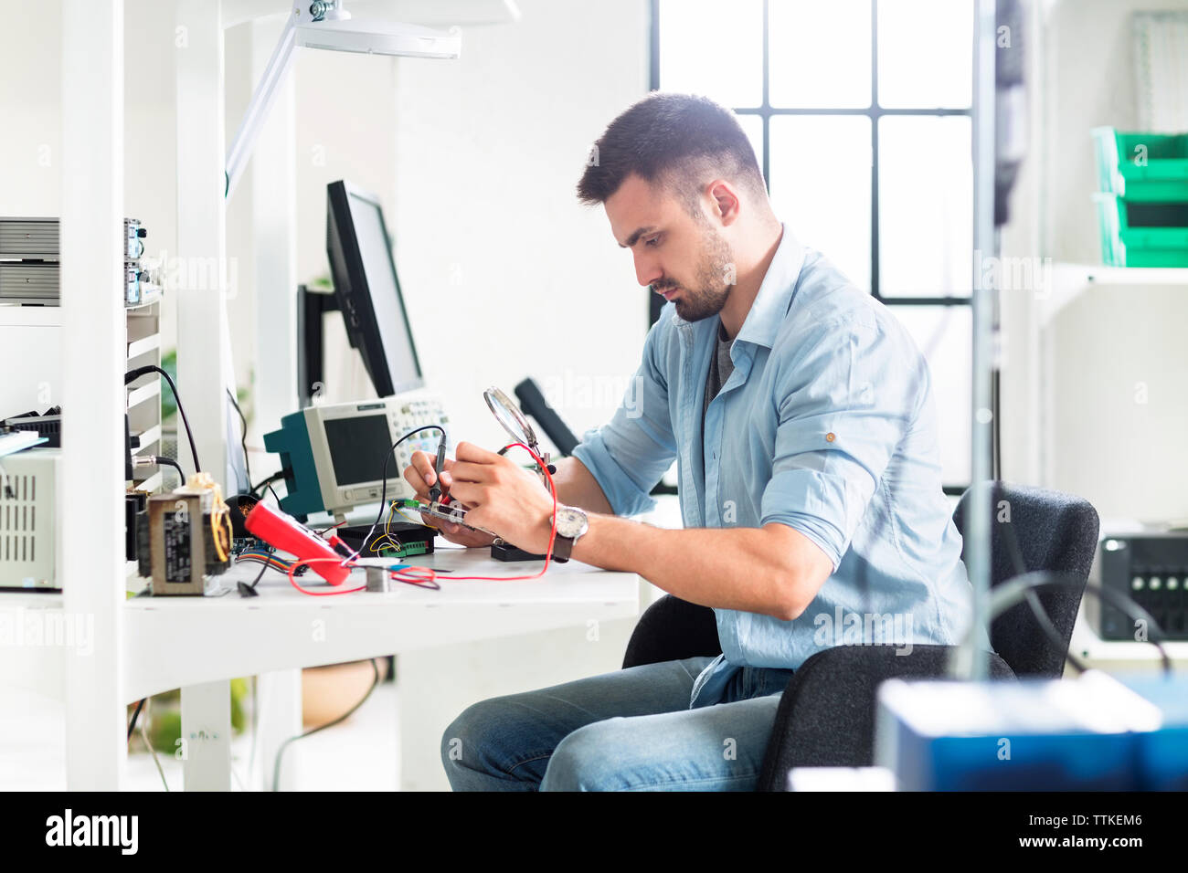 Serious engineer working at table in electronics laboratory Stock Photo