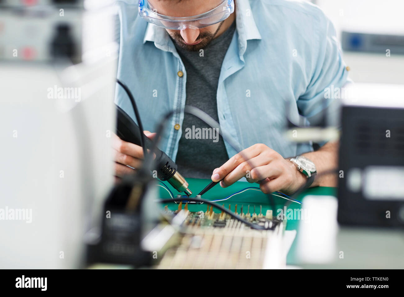 Serious technician working at table in electronics industry Stock Photo