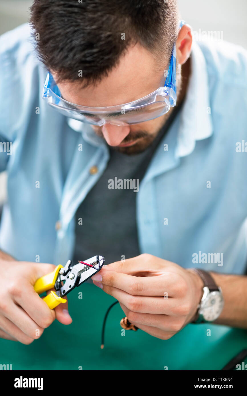 Serious technician using diagonal pliers in electronics industry Stock Photo