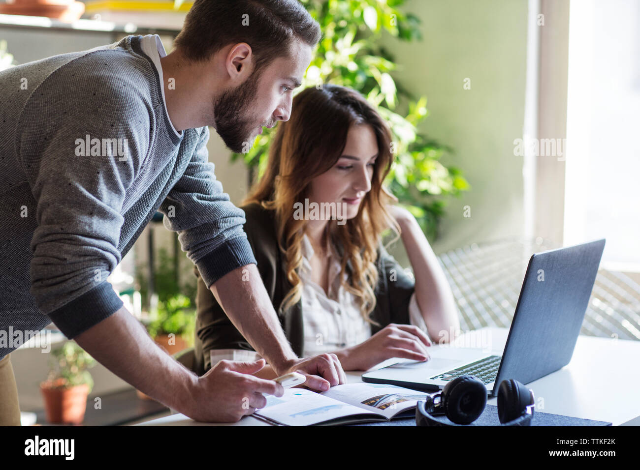 Friends using laptop computer while sitting at table in college Stock Photo
