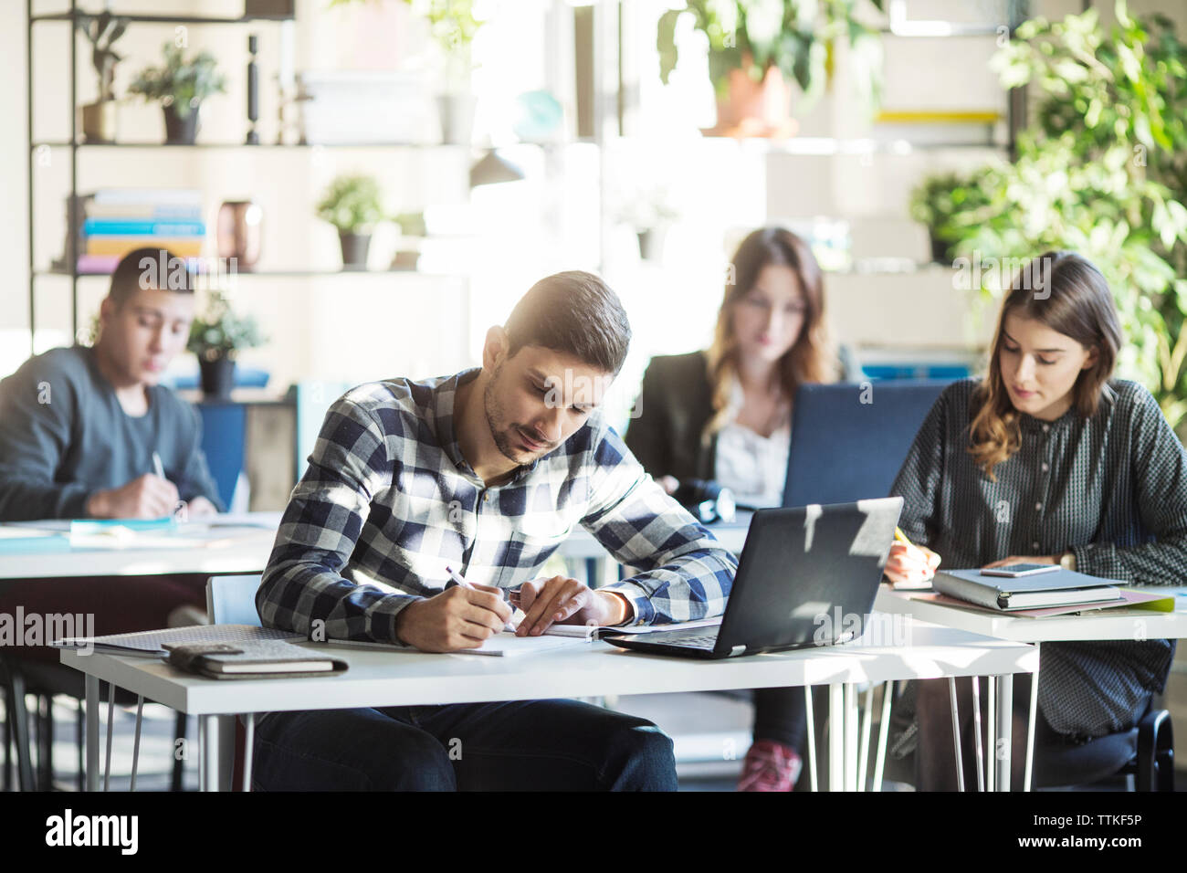 Students sitting at tables during lesson in classroom Stock Photo