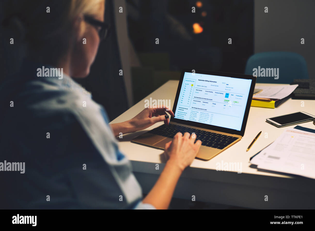 Side view of businesswoman using laptop computer while sitting at desk ...