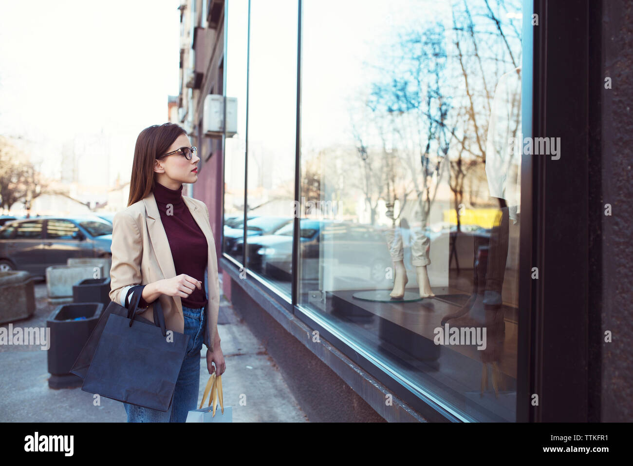 Woman looking in shop window while shopping in city Stock Photo